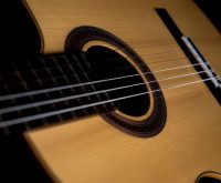 Primer plano de guitarra flamenca con cuerdas tensas, luz cálida sobre madera artesanal