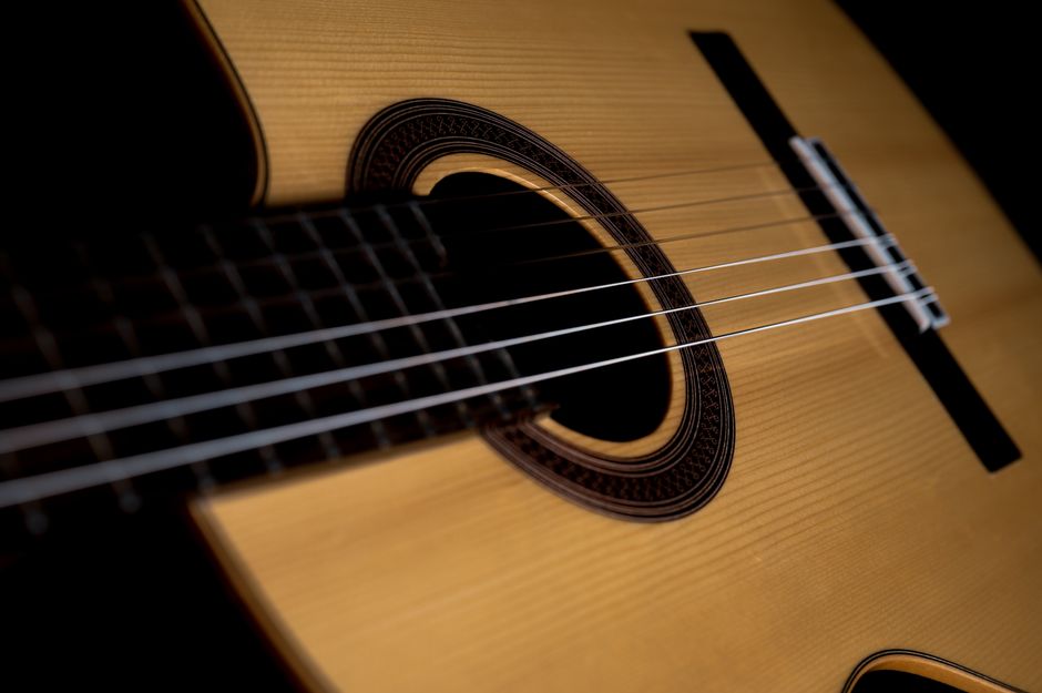 Primer plano de guitarra flamenca con cuerdas tensas, luz cálida sobre madera artesanal