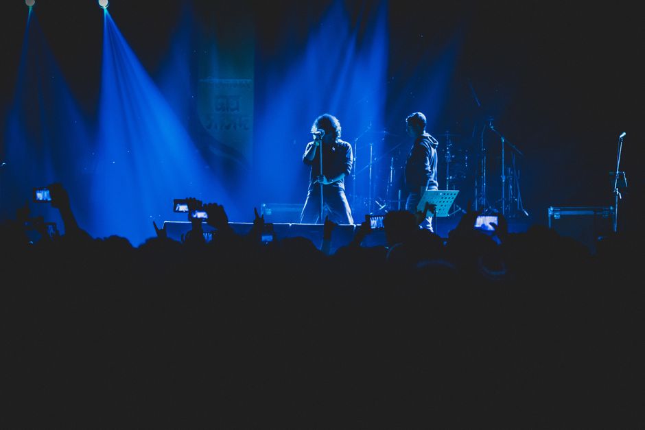 Escenario de rock iluminado con focos intensos durante un concierto en directo