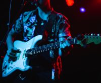 Concierto de pop-punk con guitarras y atmósfera energética bajo luces de escenario