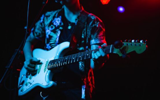 Concierto de pop-punk con guitarras y atmósfera energética bajo luces de escenario