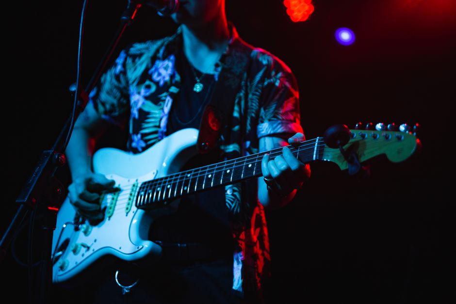 Concierto de pop-punk con guitarras y atmósfera energética bajo luces de escenario