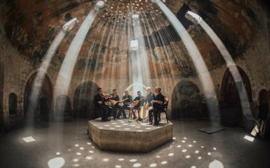 Ambiente íntimo de concierto folk acústico con iluminación cálida y atmósfera cercana
