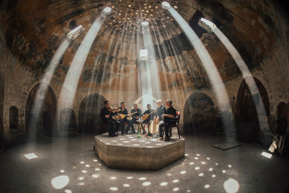 Ambiente íntimo de concierto folk acústico con iluminación cálida y atmósfera cercana