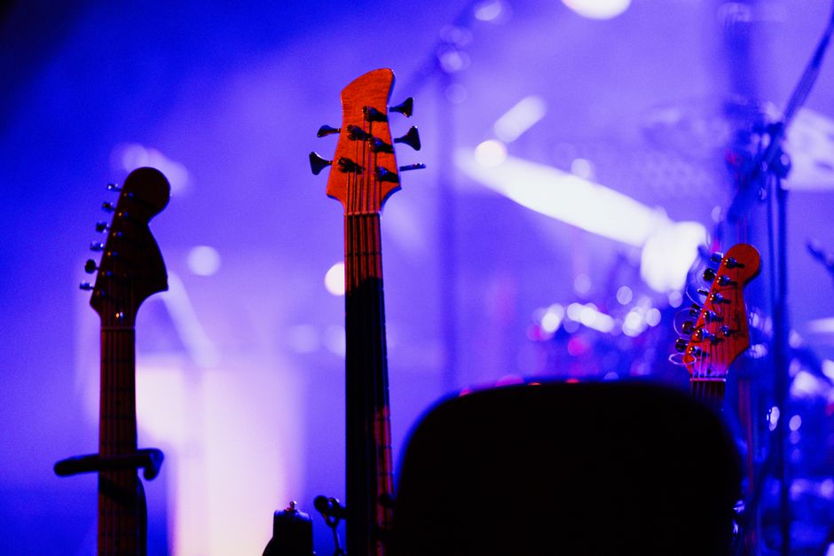 Escenario de concierto de rock con guitarras eléctricas e iluminación intensa, atmósfera blues-rock