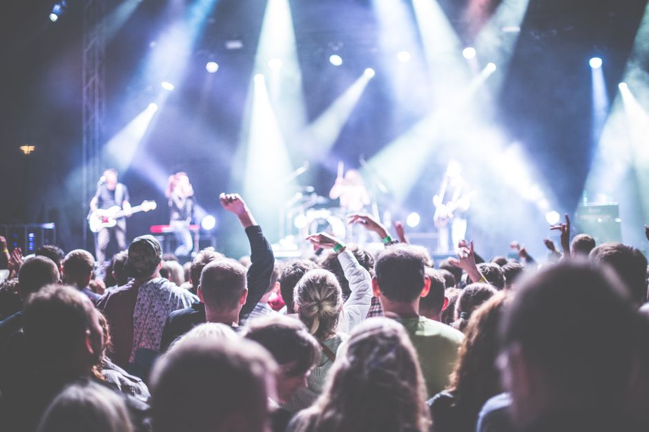 Escenario de concierto de rock con iluminación intensa y ambiente multitudinario