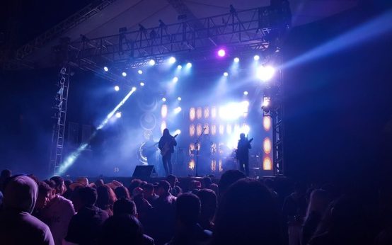 Ambiente de concierto en arena con luces intensas y público expectante