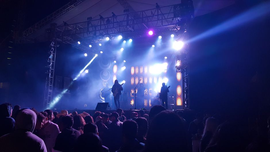 Ambiente de concierto en arena con luces intensas y público expectante