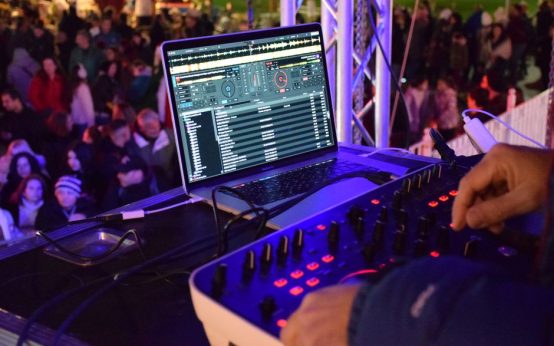 Ambiente de festival de música electrónica con luces y equipo de DJ