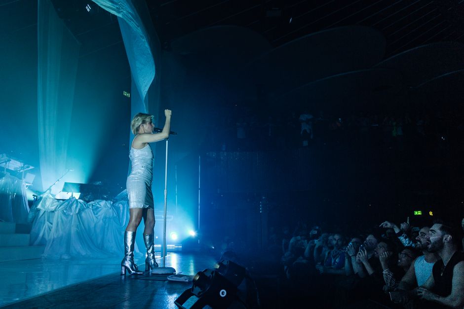 Escenario de concierto pop con micrófono y luces cálidas