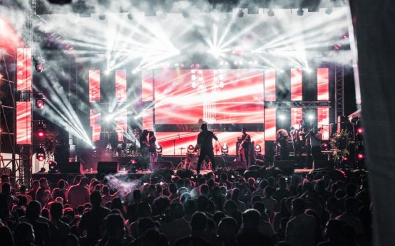 Ambiente de concierto nocturno con luces de escenario y público expectante