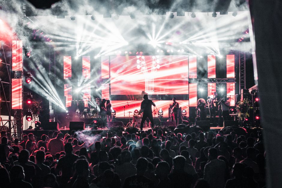Ambiente de concierto nocturno con luces de escenario y público expectante