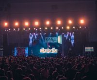 Atmósfera de celebración en un concierto con escenario iluminado y público festivo