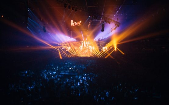 Ambiente de concierto nocturno con luces de escenario y público expectante