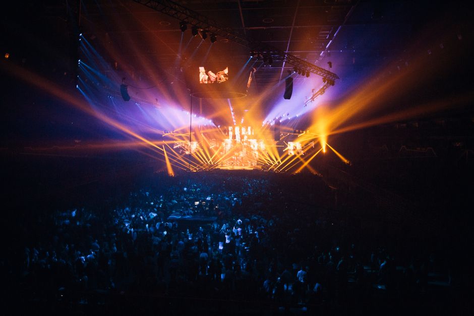 Ambiente de concierto nocturno con luces de escenario y público expectante