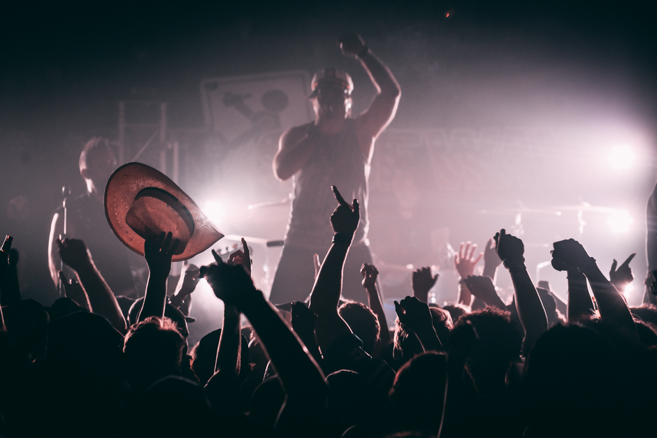 Imagen ilustrativa de la atmósfera de un concierto de indie-pop con escenario iluminado y público