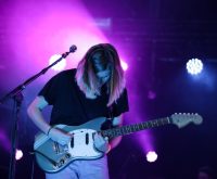 Escenario de concierto de rock indie con iluminación tenue y ambiente intimista