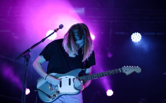 Escenario de concierto de rock indie con iluminación tenue y ambiente intimista