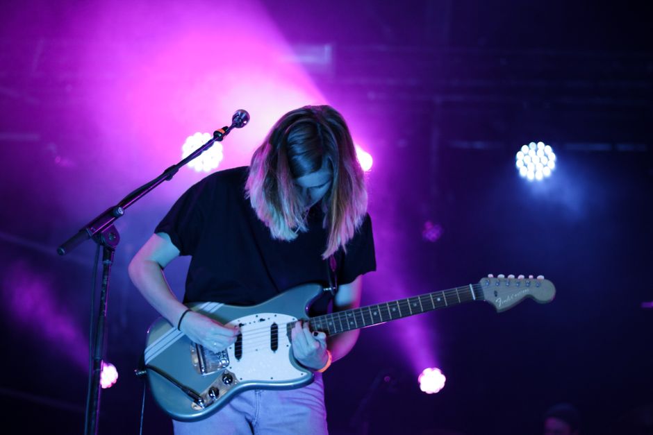 Escenario de concierto de rock indie con iluminación tenue y ambiente intimista