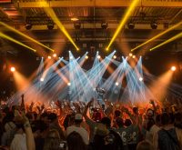 Escenario de concierto con luces intensas y público en ambiente nocturno