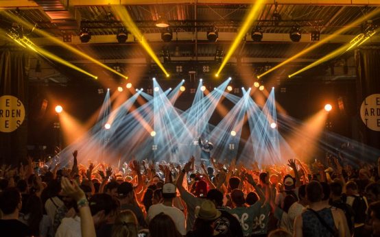Escenario de concierto con luces intensas y público en ambiente nocturno