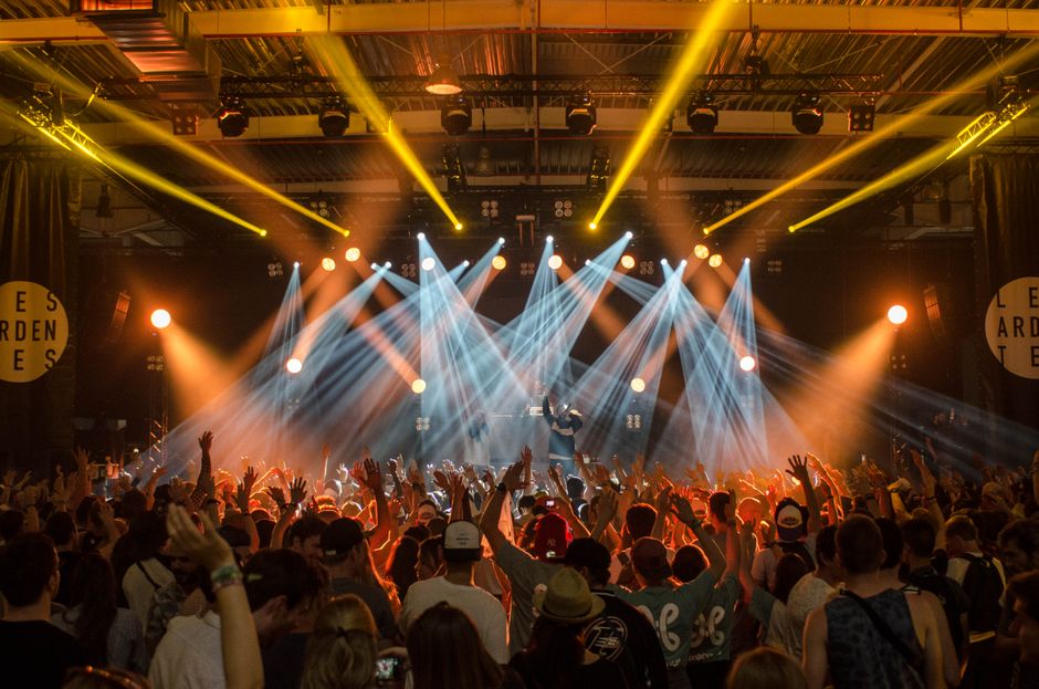 Escenario de concierto con luces intensas y público en ambiente nocturno