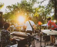 Escenario principal de festival de música al atardecer con luces de producción