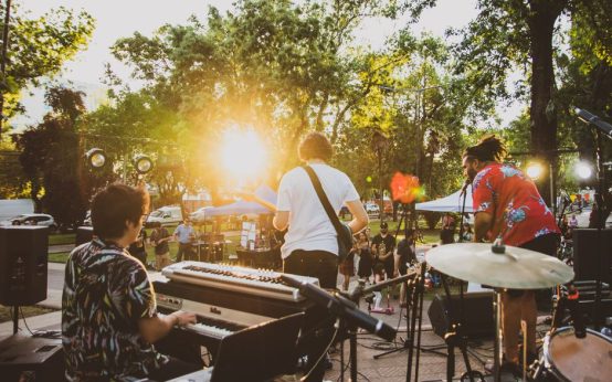 Escenario principal de festival de música al atardecer con luces de producción