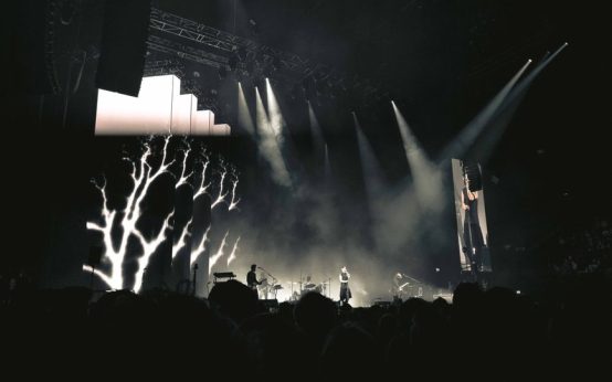 Escenario de concierto de rock industrial con luces intensas y humo