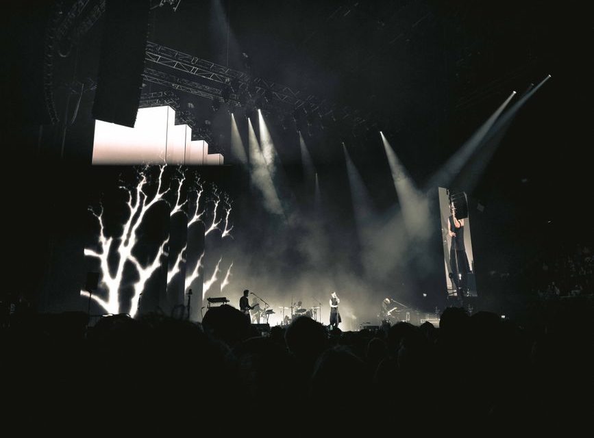 Escenario de concierto de rock industrial con luces intensas y humo