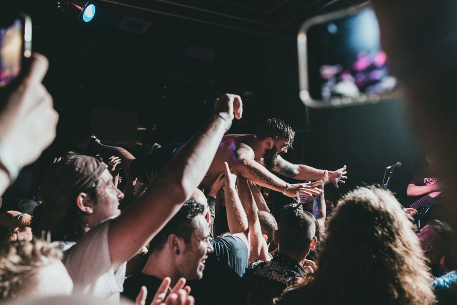 Ambiente de concierto indie rock con escenario iluminado y público
