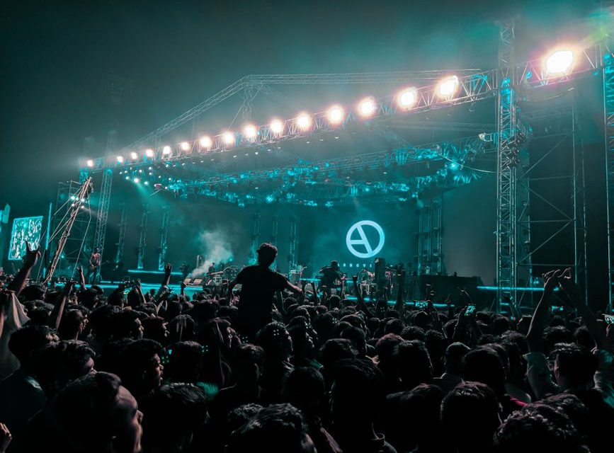 Escenario de concierto pop iluminado con público presente
