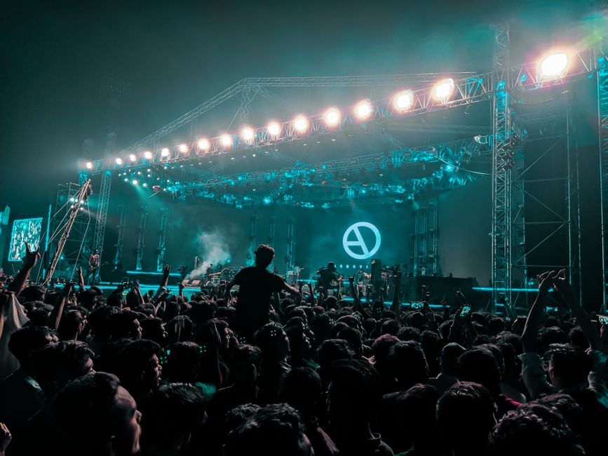 Escenario de concierto pop iluminado con público presente