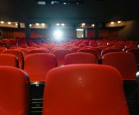 Sala de cine con pantalla iluminada y ambiente de proyección cinematográfica