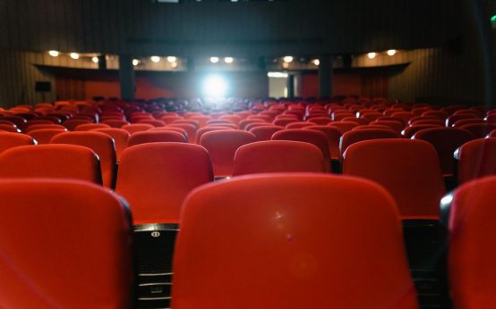 Sala de cine con pantalla iluminada y ambiente de proyección cinematográfica