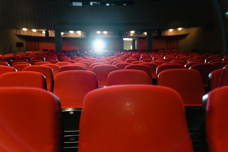 Sala de cine con pantalla iluminada y ambiente de proyección cinematográfica