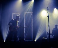 Escenario de concierto de rock con guitarra acústica bajo focos, atmósfera íntima y emotiva