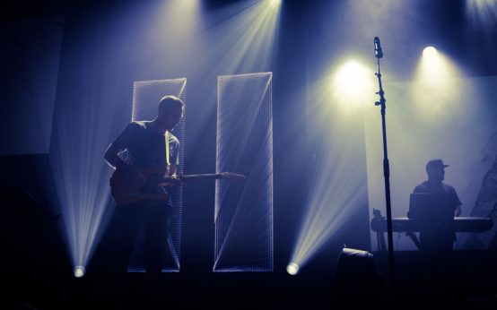 Escenario de concierto de rock con guitarra acústica bajo focos, atmósfera íntima y emotiva