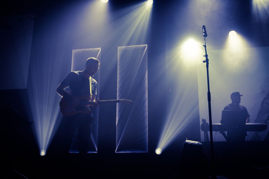 Escenario de concierto de rock con guitarra acústica bajo focos, atmósfera íntima y emotiva