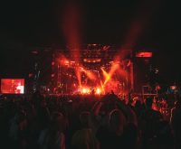 Atmósfera de concierto pop con iluminación escénica y público celebrando