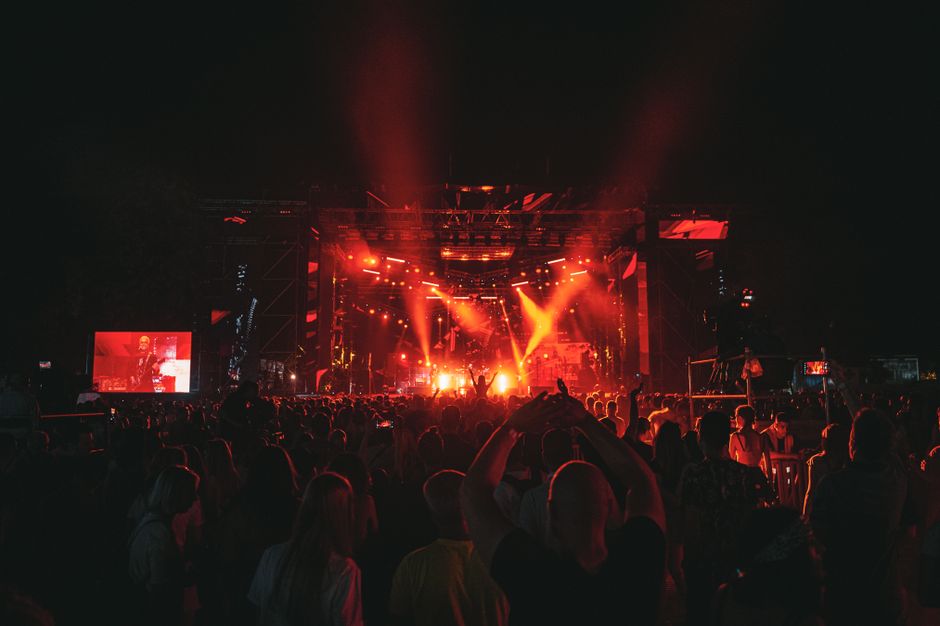 Atmósfera de concierto pop con iluminación escénica y público celebrando