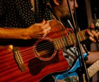 Escenario de música country con guitarra acústica bajo luces cálidas