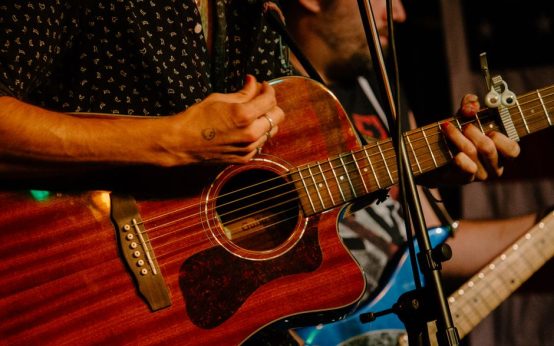 Escenario de música country con guitarra acústica bajo luces cálidas