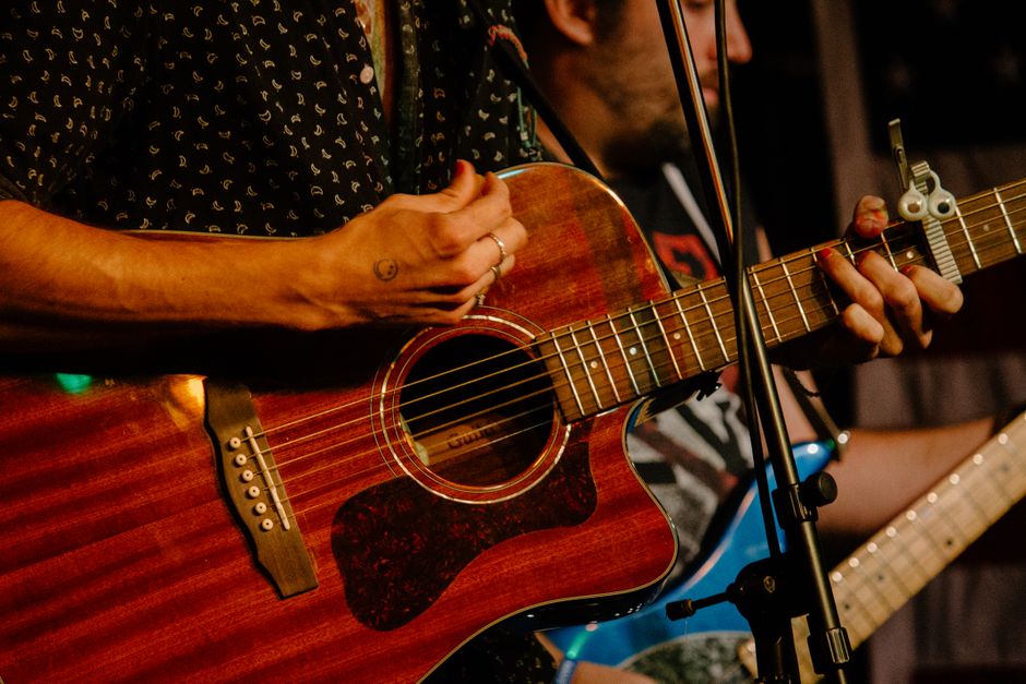 Escenario de música country con guitarra acústica bajo luces cálidas