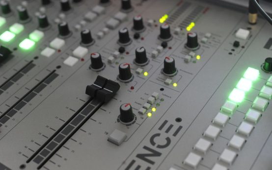 Atmósfera de estudio de grabación profesional con consola de mezclas e iluminación cálida