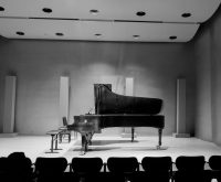 Piano de cola sobre escenario de teatro con iluminación intimista