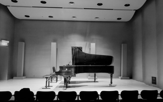 Piano de cola sobre escenario de teatro con iluminación intimista