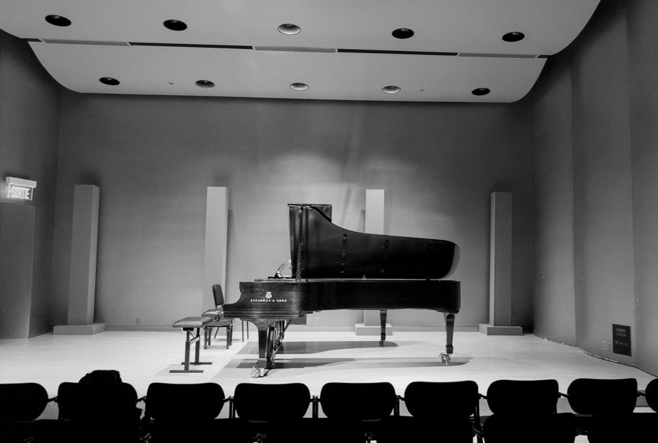 Piano de cola sobre escenario de teatro con iluminación intimista
