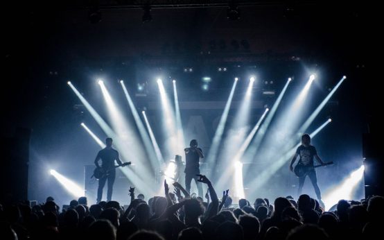 Escenario de concierto post-rock con iluminación atmosférica y equipamiento de guitarra