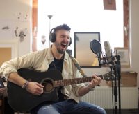 Estudio de grabación acústico con guitarra y micrófono preparados para sesión